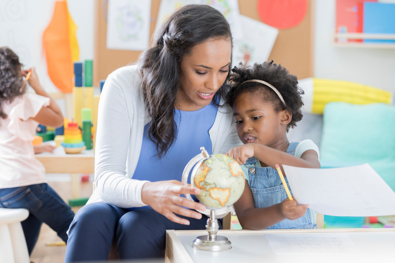 Child care worker answers little girl's questions about a globe